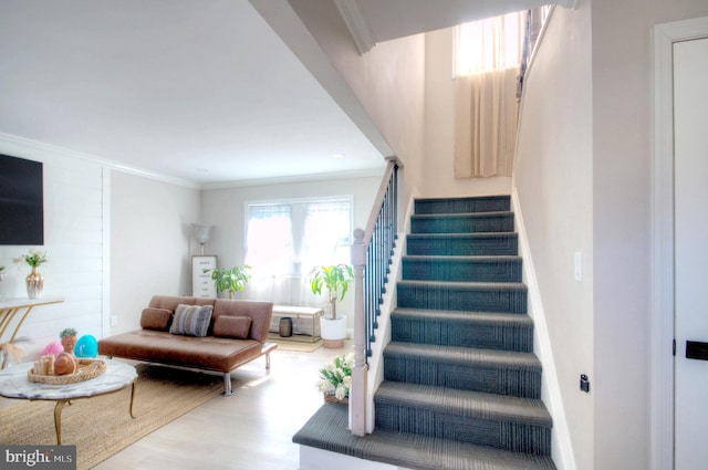 staircase featuring ornamental molding, wood finished floors, and baseboards