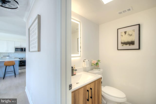 half bath featuring toilet, vanity, backsplash, and visible vents