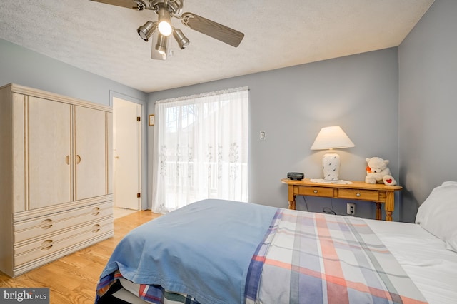 bedroom featuring a textured ceiling, a ceiling fan, and light wood-style floors