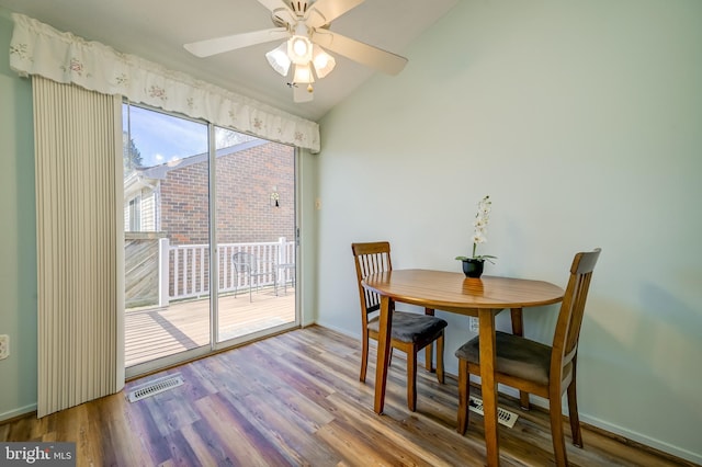 dining room with lofted ceiling, baseboards, visible vents, and wood finished floors