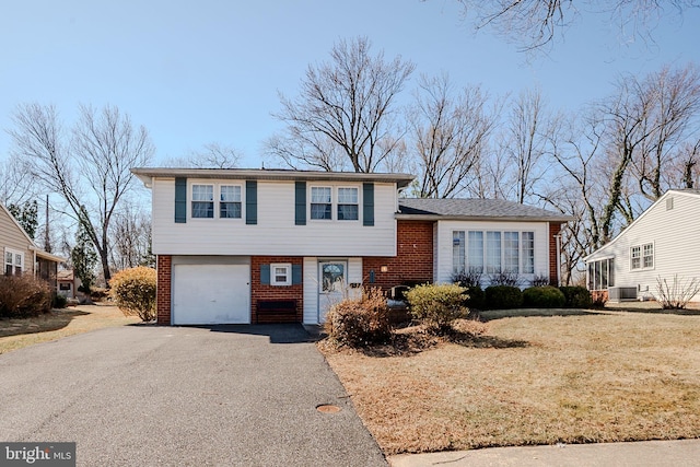 tri-level home featuring brick siding, a garage, driveway, and central AC