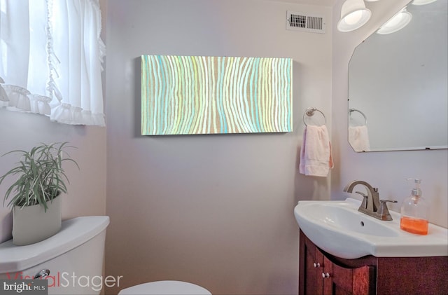 bathroom featuring visible vents, toilet, and vanity