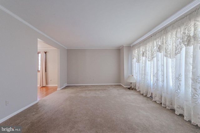 carpeted spare room featuring baseboards and ornamental molding