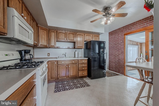 kitchen featuring white appliances, light floors, brick wall, and a sink