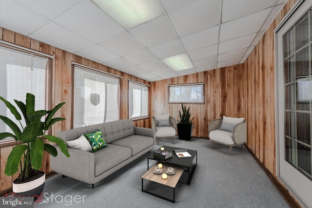 living room featuring a paneled ceiling, carpet, and wood walls