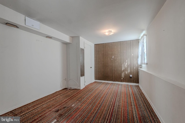 unfurnished bedroom featuring baseboards, carpet, and wooden walls