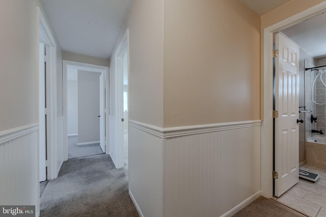 hallway featuring carpet flooring and wainscoting