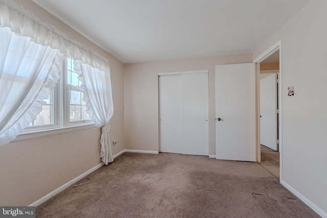 unfurnished bedroom featuring carpet flooring, baseboards, and a closet