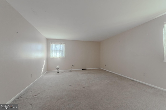 unfurnished room with baseboards and light carpet