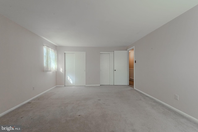 unfurnished bedroom with baseboards, multiple closets, and carpet floors