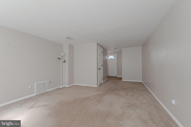 empty room featuring baseboards, visible vents, and light carpet