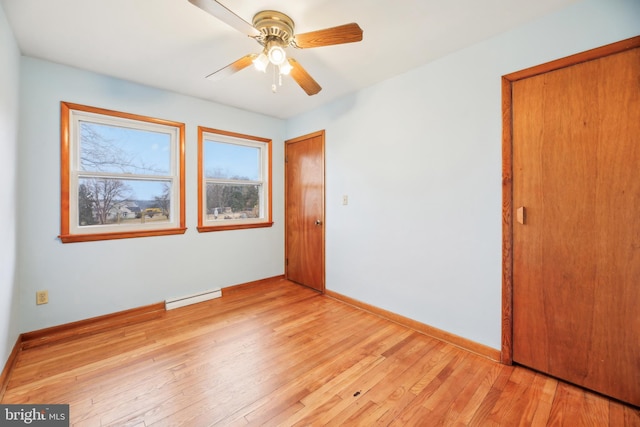 unfurnished bedroom featuring a baseboard radiator, a closet, light wood-style floors, a ceiling fan, and baseboards