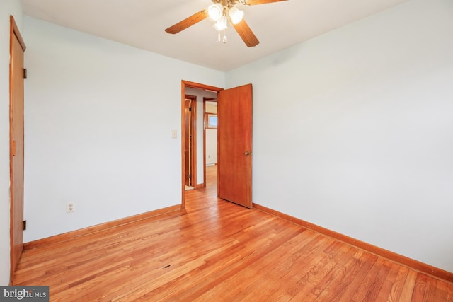 spare room featuring light wood finished floors, ceiling fan, and baseboards