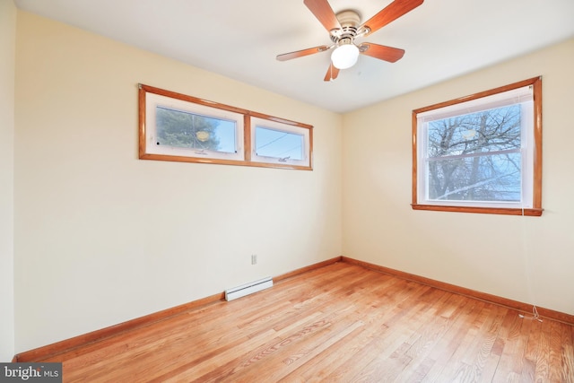 empty room with a baseboard heating unit, light wood-style floors, plenty of natural light, and baseboards