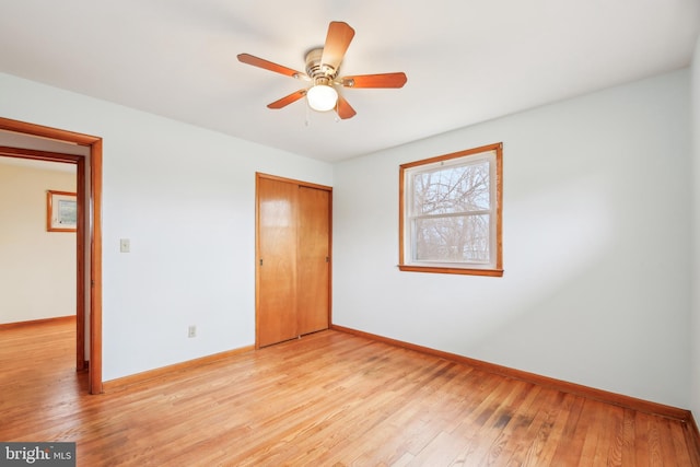 unfurnished bedroom featuring a closet, baseboards, ceiling fan, and light wood finished floors