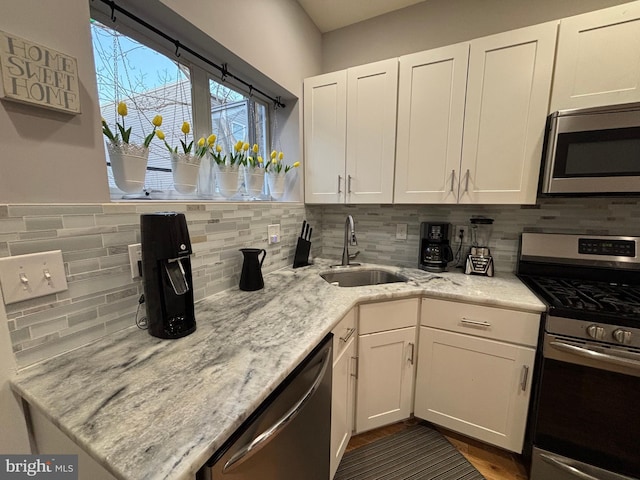 kitchen with white cabinetry, a sink, appliances with stainless steel finishes, and decorative backsplash
