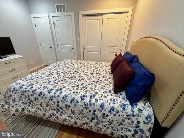 bedroom featuring a closet, baseboards, visible vents, and wood finished floors
