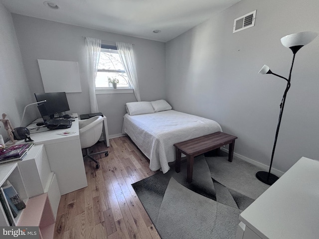 bedroom featuring baseboards, visible vents, and light wood finished floors