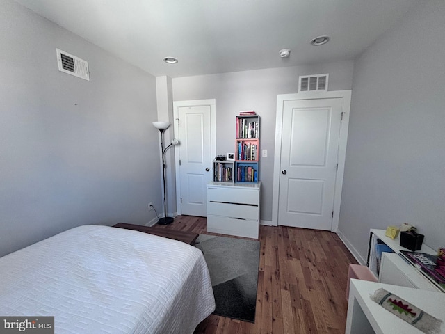 bedroom with dark wood finished floors, baseboards, and visible vents