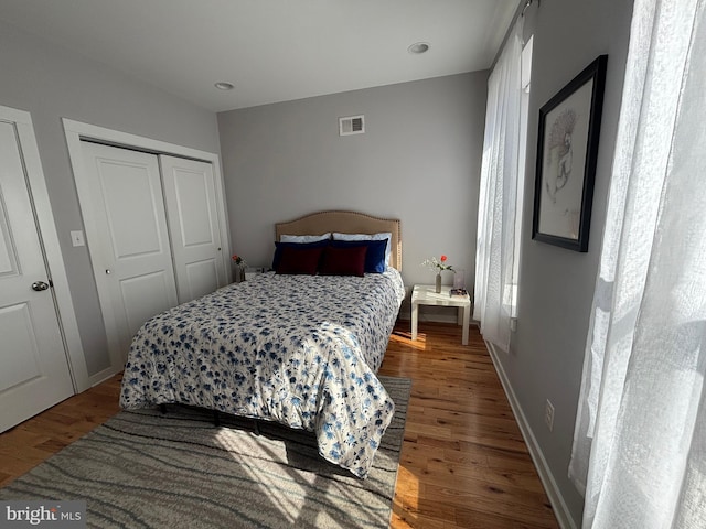 bedroom featuring visible vents, baseboards, a closet, and wood finished floors