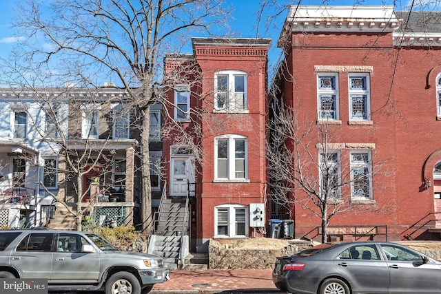 view of front facade featuring brick siding and stairway