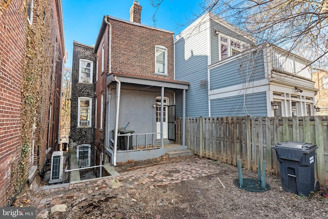 back of property featuring fence private yard, a chimney, and brick siding