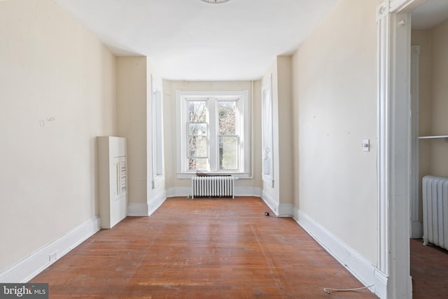 interior space with radiator heating unit, baseboards, and wood finished floors