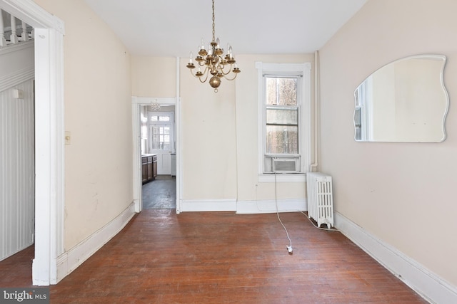 unfurnished dining area with an inviting chandelier, radiator heating unit, baseboards, and dark wood-type flooring