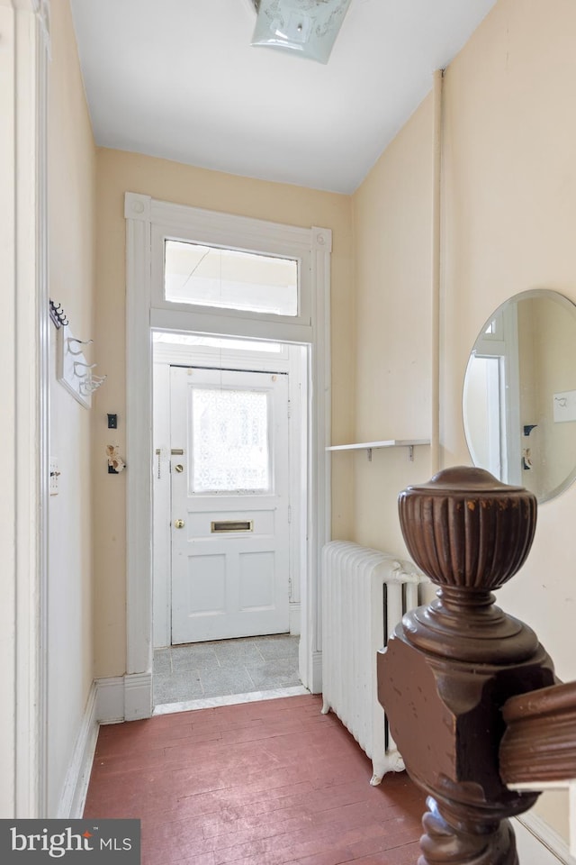 entryway with radiator heating unit, baseboards, and wood finished floors