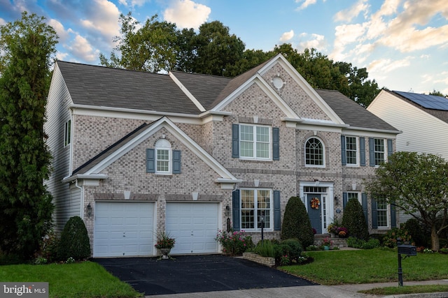 view of front of home with an attached garage, a front lawn, aphalt driveway, and brick siding