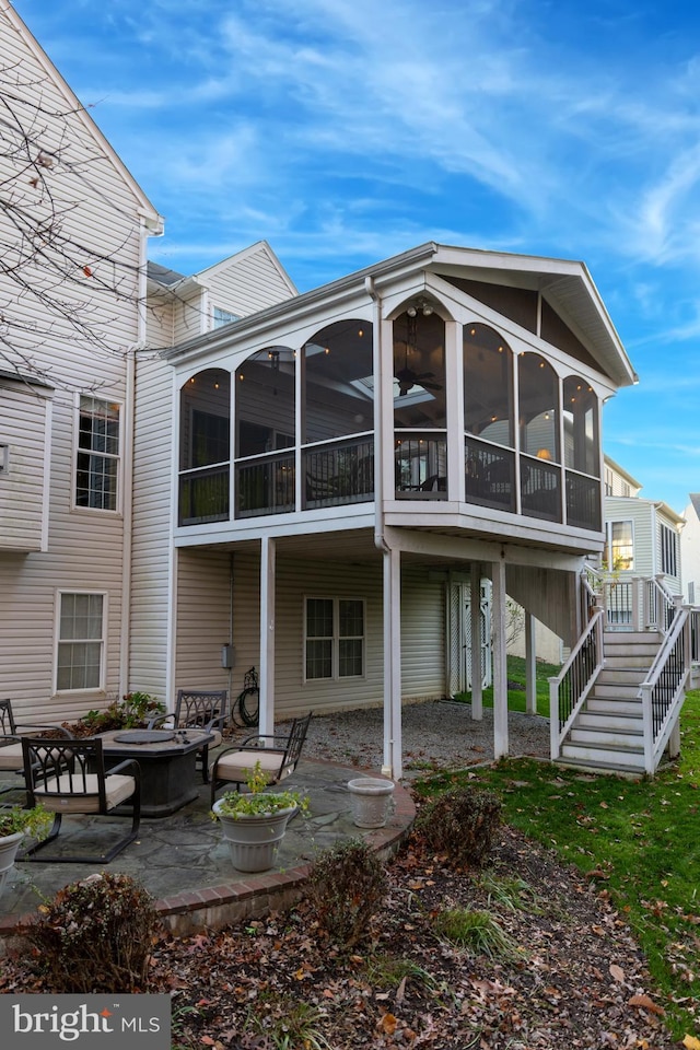 rear view of property with a sunroom, stairs, and a patio area