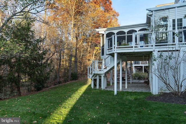 rear view of property featuring a sunroom, a yard, and stairs