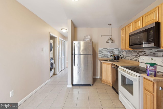 kitchen with stacked washer and dryer, decorative backsplash, appliances with stainless steel finishes, light brown cabinets, and a sink