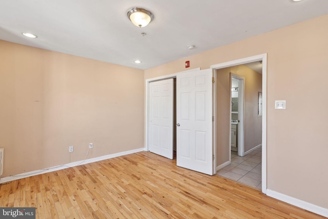 unfurnished bedroom with light wood-style flooring, baseboards, a closet, and recessed lighting