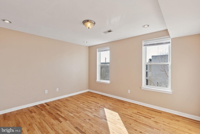 empty room with light wood-style floors, visible vents, baseboards, and recessed lighting