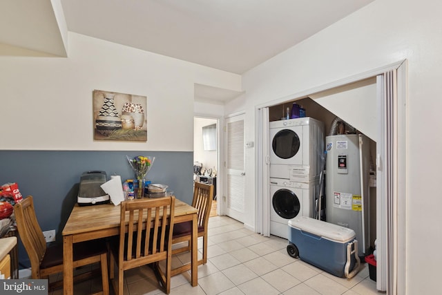 interior space with stacked washer / dryer, electric water heater, and light tile patterned floors