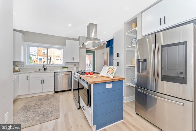 kitchen featuring open shelves, island exhaust hood, stainless steel appliances, wood counters, and a sink