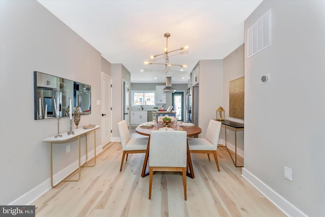 dining area featuring a chandelier, visible vents, light wood-type flooring, and baseboards