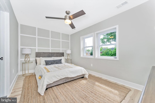 bedroom featuring visible vents, baseboards, wood finished floors, and a ceiling fan