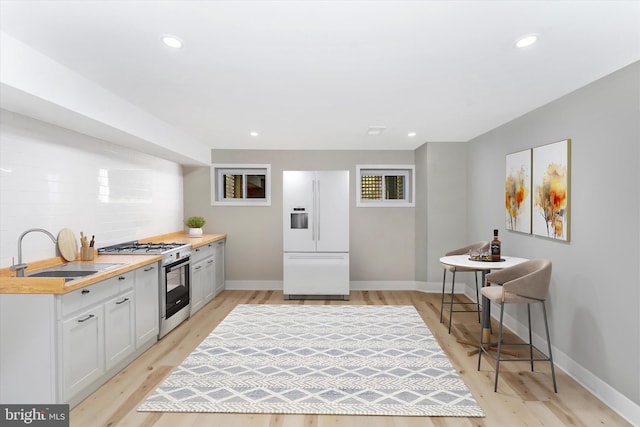 kitchen with gas stove, recessed lighting, a sink, light countertops, and white refrigerator with ice dispenser