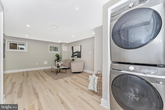 laundry area with laundry area, recessed lighting, stacked washer / drying machine, and wood finished floors