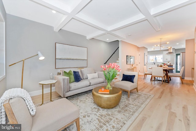 living area featuring beamed ceiling, coffered ceiling, baseboards, and light wood-style floors