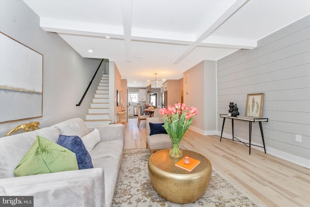 living room featuring beamed ceiling, stairs, baseboards, and wood finished floors