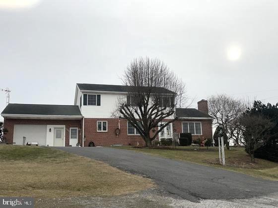 traditional home with driveway, a garage, a chimney, a front lawn, and brick siding