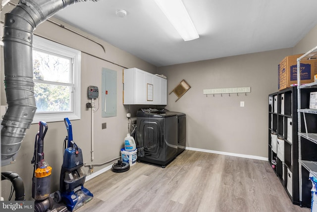 clothes washing area with cabinet space, electric panel, baseboards, wood finished floors, and independent washer and dryer