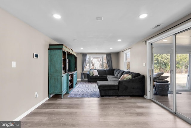 living room with light wood-type flooring, visible vents, baseboards, and recessed lighting