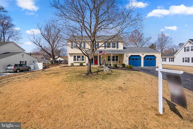 view of front of house with an attached garage, a front lawn, fence, and aphalt driveway