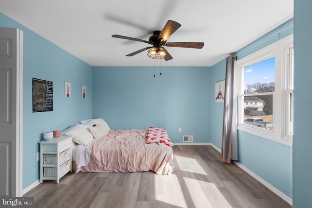 bedroom with baseboards, visible vents, ceiling fan, and wood finished floors