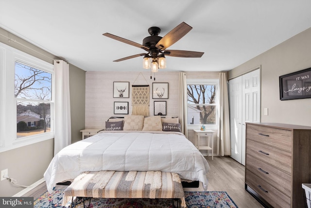 bedroom featuring light wood finished floors, a closet, a ceiling fan, and baseboards