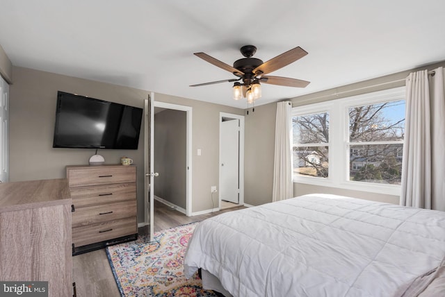 bedroom featuring a ceiling fan, light wood-style flooring, and baseboards